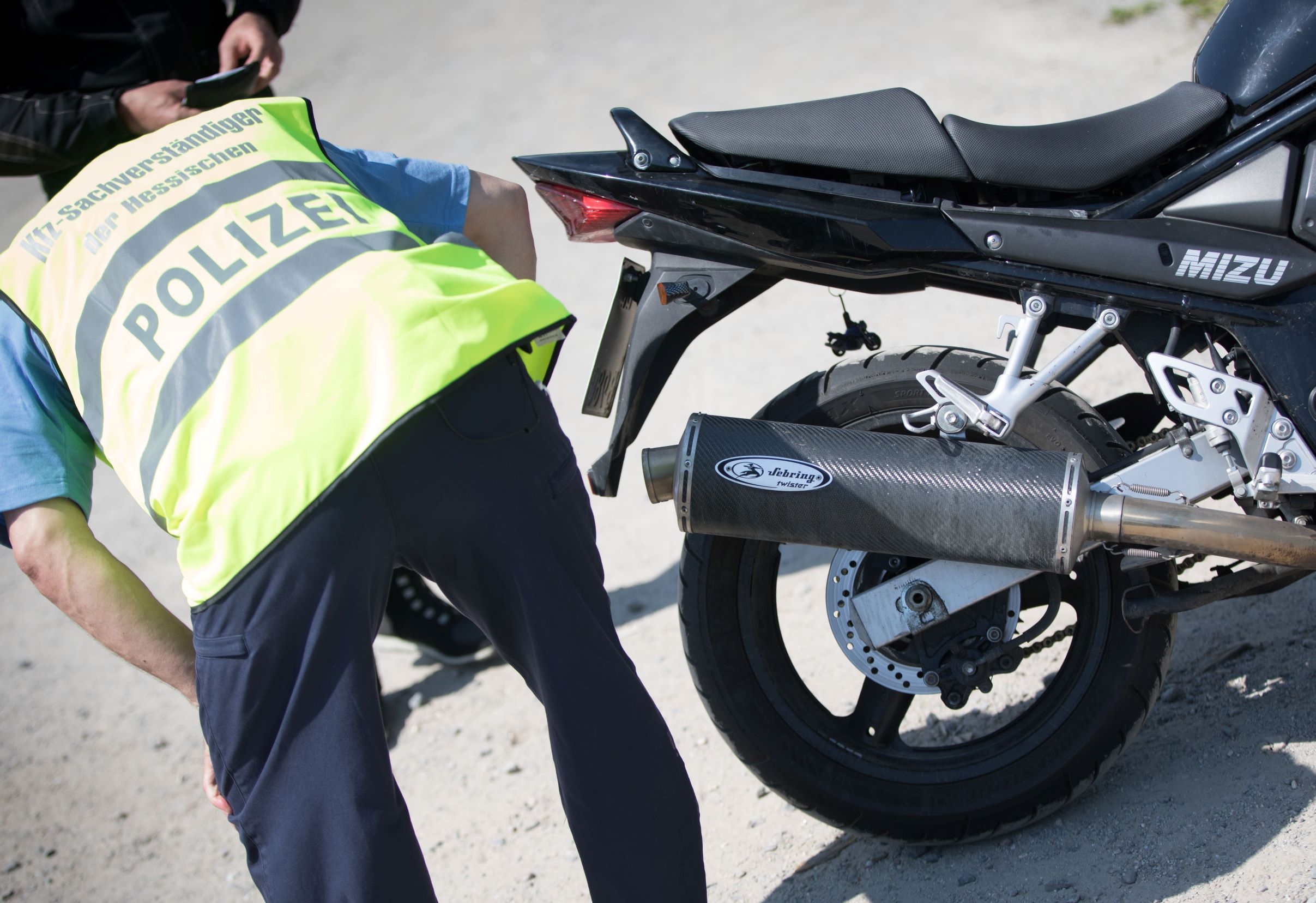 A police officer checks how loud a motorcycle exhaust pipe is